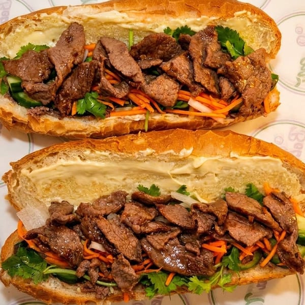 Two delicious Bò Lá Lốt Banh Mi sandwiches with grilled beef, pickled vegetables, and cilantro.